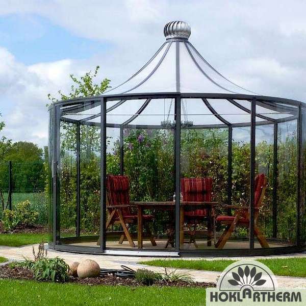 Rotating glass pavilion in the garden with table and chairs